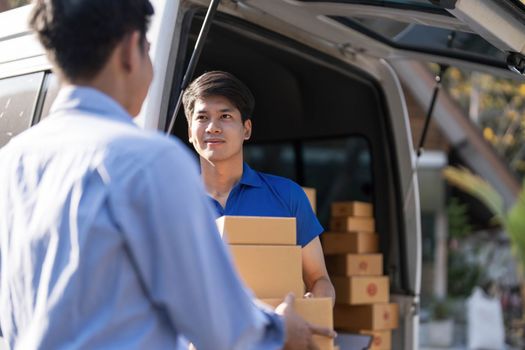 Asian deliveryman delivering package box parcel giving to male customer signing using smart technology tablet at home delivery service logistics business ordering mail