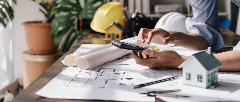 Image of engineer drawing a blue print design building or house, An engineer workplace with blueprints, pencil, protractor and safety helmet, Industry concept..