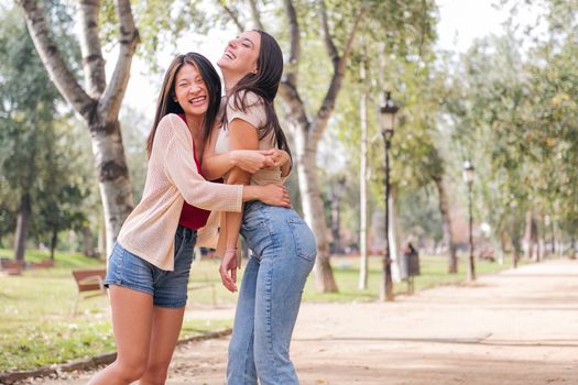 couple of happy women having fun and laughing during a date in a park, concept of friendship and love between people of the same sex