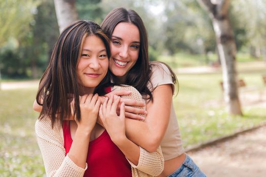 couple of happy women looking at camera embracing and smiling during a date in a park, concept of friendship and love between people of the same sex, copy space for text
