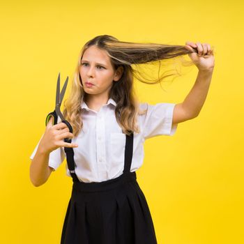 Teenage school girl with scissors, isolated on yellow background. Child creativity, art and crafts.
