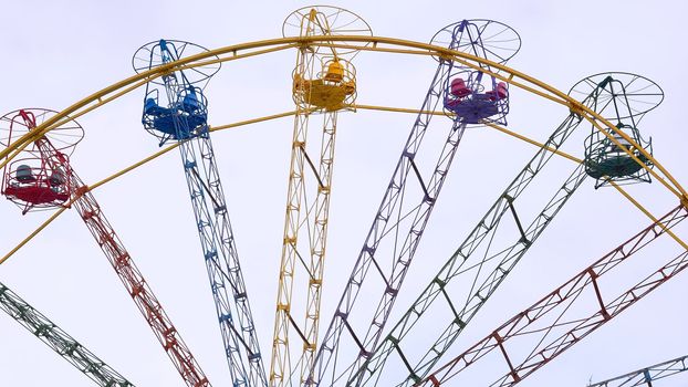 an amusement park or fairground ride consisting of a giant vertical revolving wheel with passenger cars suspended on its outer edge.