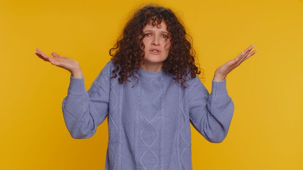 What Why. Sincere irritated woman raising hands in indignant expression asking reason of failure demonstrating disbelief irritation by trouble. Confused curly haired girl isolated on yellow background
