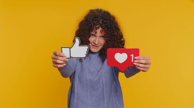 Like. Curly haired woman raises inscription thumbs up banner thumbs up agrees with something, gives positive reply recommends advertisement likes good on social media. Young girl on yellow background