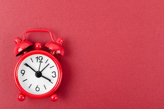 Red alarm clock on red colour background.