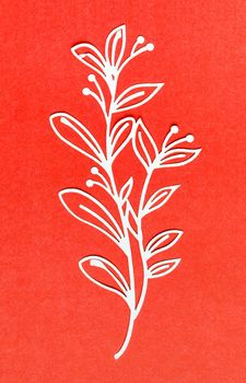 The Carve of white paper flower on a red cardboard background.