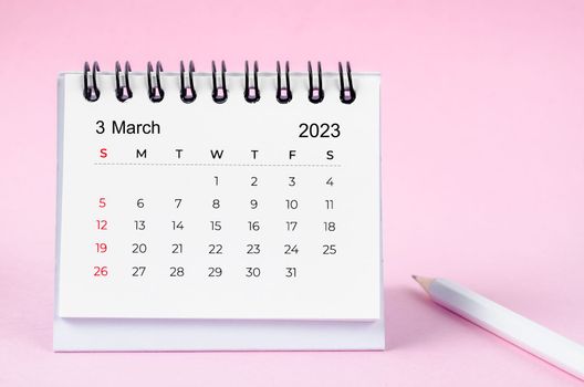 March 2023 desk calendar for 2023 year and wooden pencil on pink color background.
