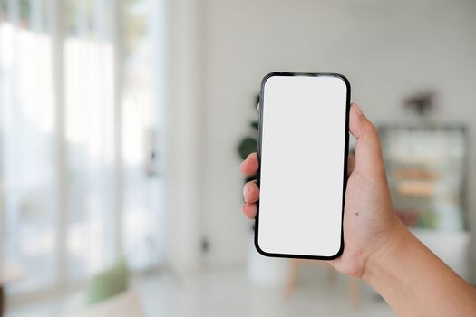 Mock up phone in woman hand showing white screen. Mobile phone white screen is blank the background is blurred.