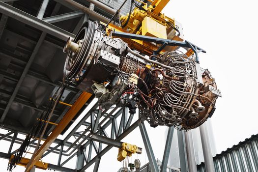 The engine of a gas turbine compressor hangs on a crane during installation in a module for generating electricity