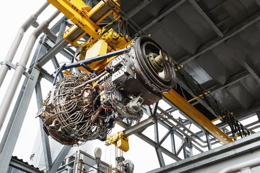 The engine of a gas turbine compressor hangs on a crane during installation in a module for generating electricity