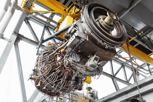 The engine of a gas turbine compressor hangs on a crane during installation in a module for generating electricity