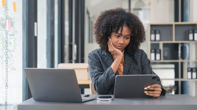 Asian Business woman using calculator and laptop for doing math finance on an office desk, tax, report, accounting, statistics, and analytical research concept..