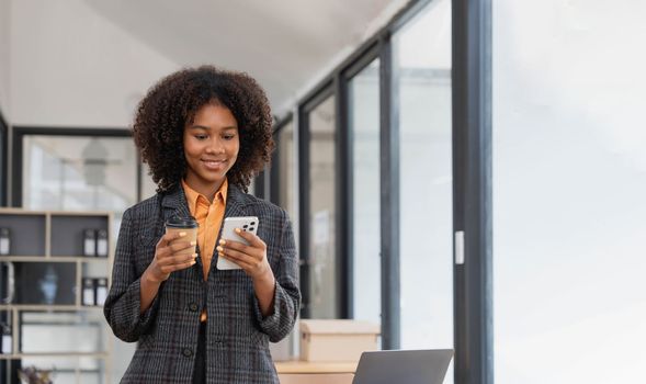 Portrait of elegant successful asian business woman speaking by smartphone and smiling happily while standing against window in office