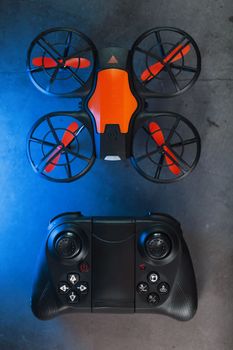 Quadcopter drone with joystick control and blue neon backlight, on a dark textured background