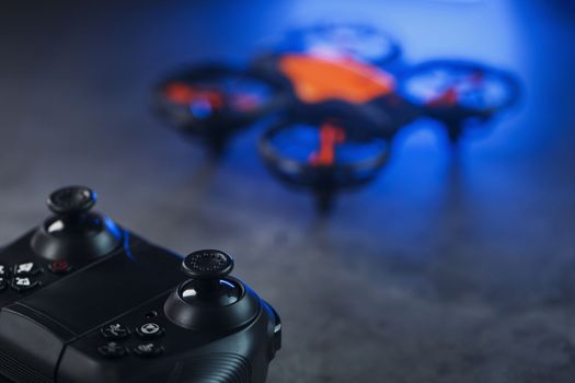 Quadcopter drone with joystick control and blue neon backlight, on a dark textured background