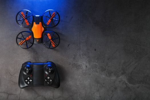 Quadcopter drone with joystick control and blue neon backlight, on a dark textured background