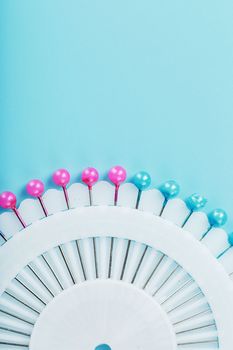 A set of multicolored needles pins in a round platform on a blue background with free space