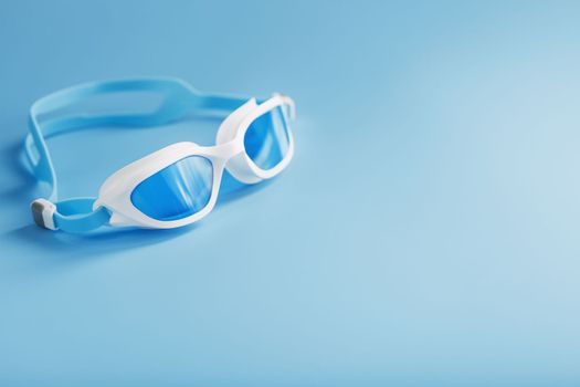 White swimming goggles on a blue background in a minimalist style with free space