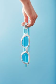 White swimming goggles on a blue background in a minimalist style with free space