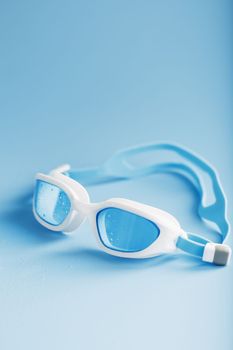 White swimming goggles on a blue background in a minimalist style with free space