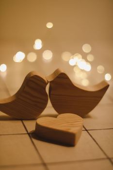 two wooden birds and heart made by bokeh lights background. Valentines day, Easter, Wedding card with wooden figures of birds, home decor.