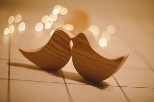 two wooden birds and heart made by bokeh lights background. Valentines day, Easter, Wedding card with wooden figures of birds, home decor.