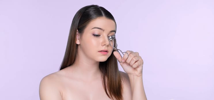 Closeup happy young charming brunette holding eyelash curler in her hand as makeup accessory. Beautiful girl applying eyelash curler in studio with isolated background for copyspace.