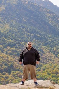 The fat man stands on the top of the mountain