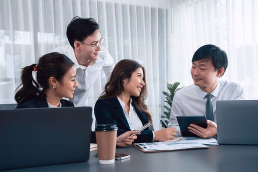 Harmony in office concept as business people analyzing dashboard paper together in workplace. Young colleagues give ideas at manager desk for discussion or strategy planning about project.