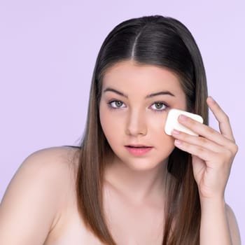 Facial cosmetic makeup concept. Portrait of young charming girl applying dry powder foundation. Beautiful girl smiling with perfect skin putting cosmetic makeup on her face.