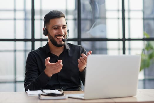 Positive businessman talking on headset at a computer