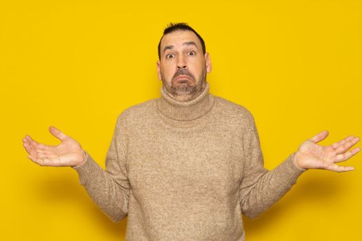 A photo of clueless emotional man dressed in beige turtleneck sweater with puzzled confused look, frowning face, shrugging because he doesn't know the reason of the accident