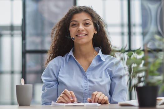 Smiling businesswoman or helpline operator with headset and computer at office