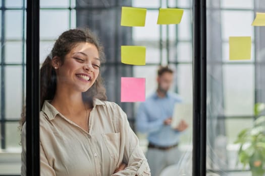 Bringing her vision to life. Shot of a confident businesswoman presenting an idea to her colleague using adhesive notes on a glass wall in the office.