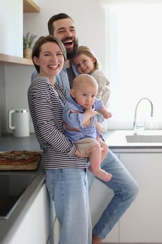 Family of 4 posing in the kitchen smiling and happy