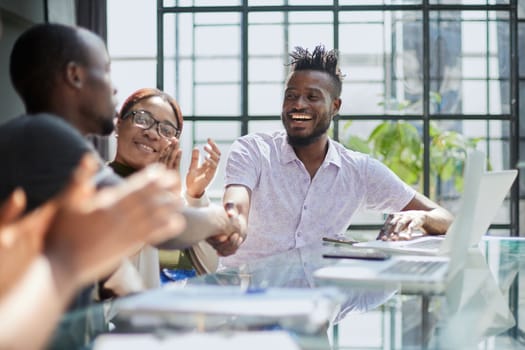 team of young african people in the office shaking hands