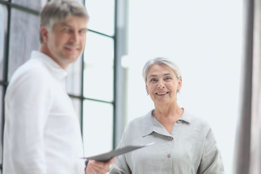 Professional business man and woman standing back to back in the office looking at the camer