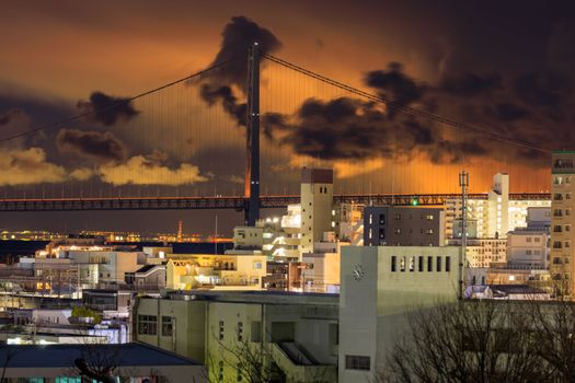 Low clouds with orange glow and suspension bridge over city apartments. High quality photo