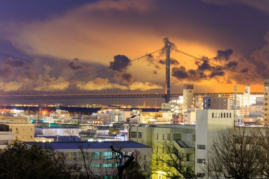 Glow from city in low clouds over Akashi Bridge and city at night. High quality photo