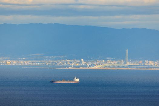 Cargo Ship Sails to Port in Osaka Bay by Rinku Gate Tower on Sunny Day. High quality photo