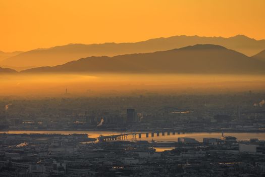 Thick layer of smog over industrial city with orange glow in sky at dawn. High quality photo