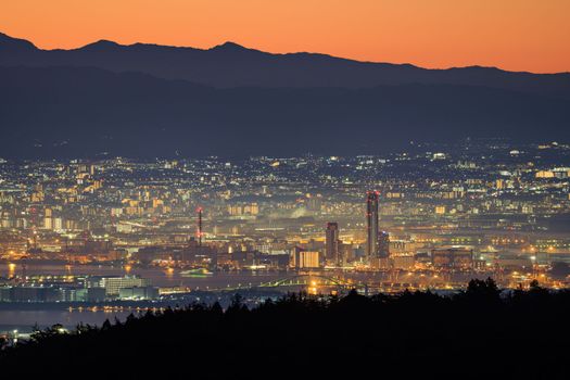 Lights from city mix with orange dawn glow over distant mountains. High quality photo