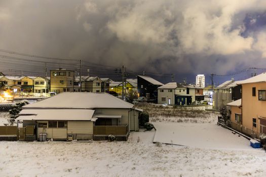 Light snow on houses in suburb at night with storm clouds overhead. High quality photo