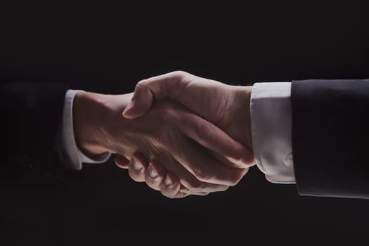 Photo of two men in suits shaking hands on a black background