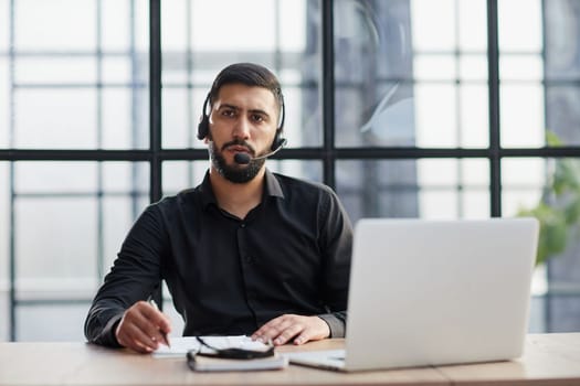 Young handsome male customer support phone operator with headset working in call center.