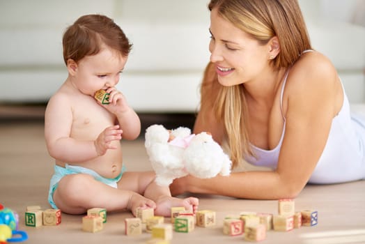 Developing her motor skills and hand-eye coordination. an adorable baby girl and her mother playing with wooden blocks at home