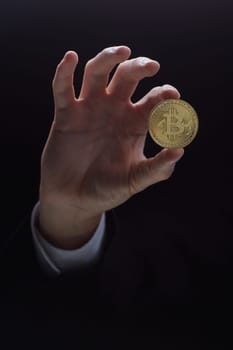 A hand holds a coin isolated on a black background