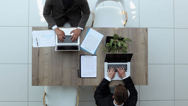 two businessmen sitting on a chair and watching something on a laptop