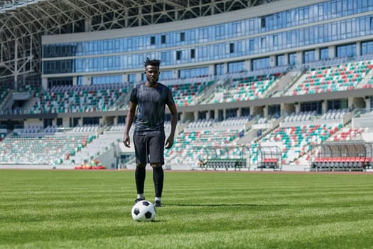 African American man playing football on the stadium field.