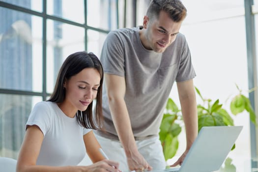 male ceo executive manager mentor giving consultation on financial operations to female colleague intern using laptop sitting in modern office